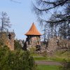 The Northern Tower of Ērģeme Medieval Castle from a distance, blue sky in the background, forest landscape in the foreground