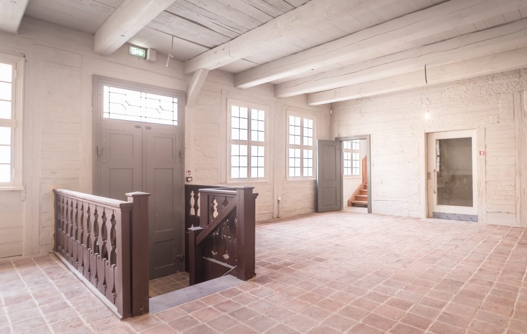 The front room of Mrs. Hoyer's guest house in white with a gray door leading to the exit