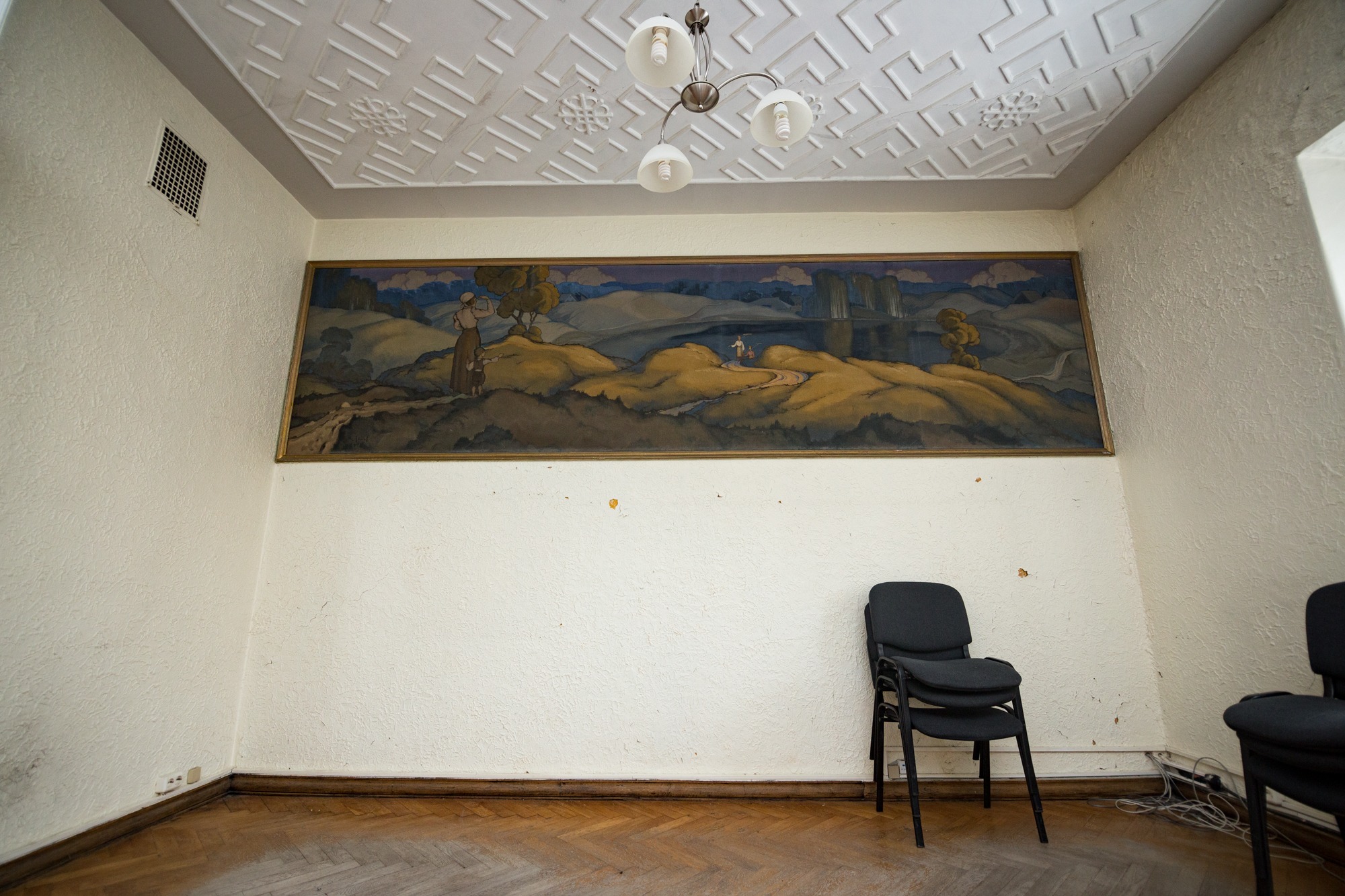 Siguldas Jaunās pils telpa ar mākslas darbu pie sienas un sēžamkrēsliem