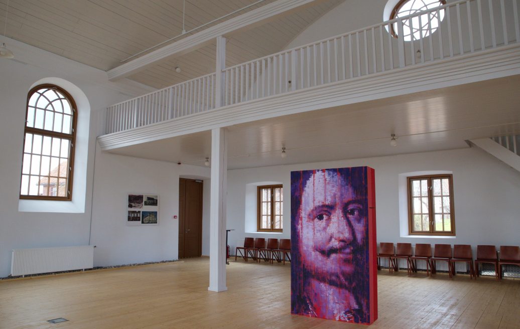 Sabile Makslas Culture and Tourism Center has a white interior with wooden chairs and artwork in the middle of the room