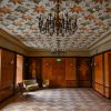 The main room of Sigulda New Palace with two chandeliers and a luxurious ceiling design of green and orange elements
