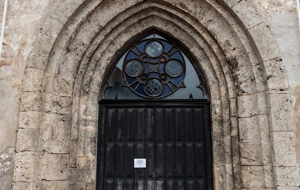 Aizvērtas Cēsu Sv. Jāņa baznīcas ieejas durvis, brūni-melnā krāsā