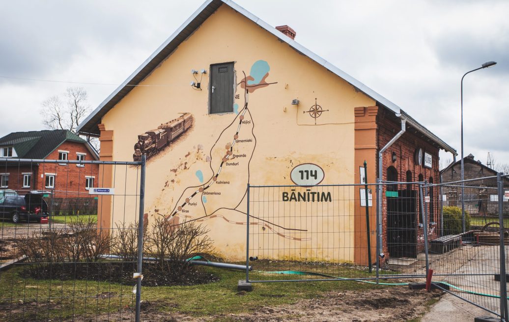 A mural with a bus stop map and a train at Alūksne Station Barn