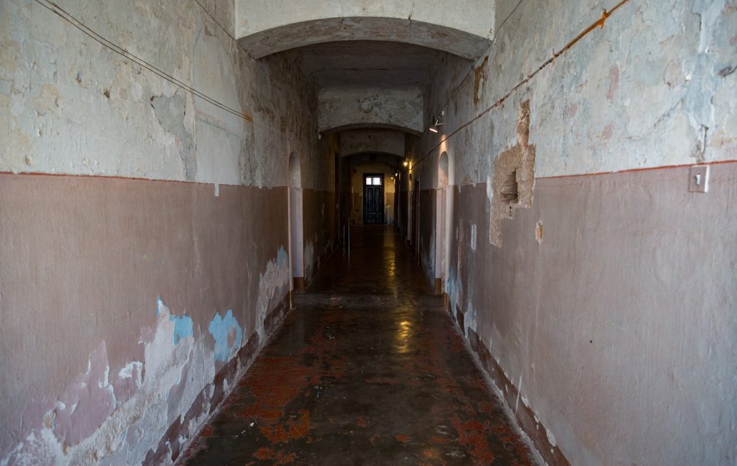Hallway of Krustpils Palace before restoration with visible damage to the walls