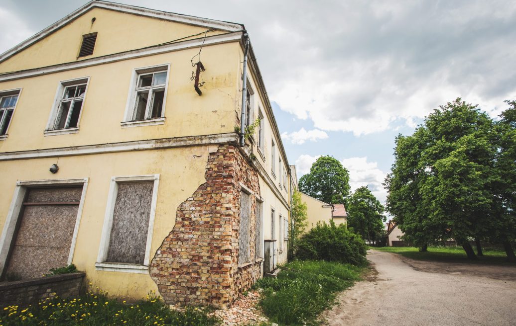 Kuldīgas mākslas un izglītības koprades telpas “Adatu fabrika” ekas skats ar daļēji nodrupušu ārsienas apdari zem kuras redzams ķieģeļu mūris