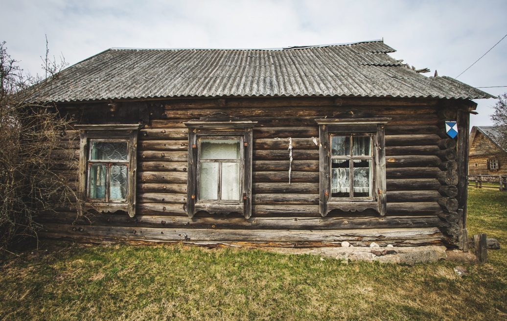 A house with three windows and a damaged roof of the Farmstead Slutišķi 2