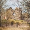 The ruins of the southern tower of Alūksne Castle in a landscape with trees