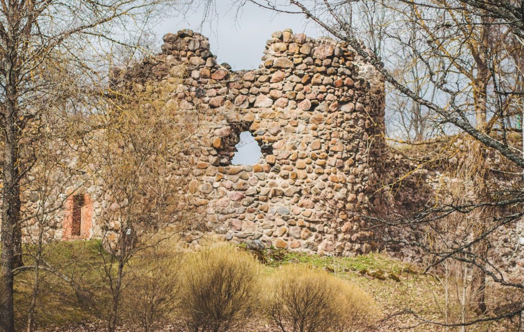 The ruins of the southern tower of Alūksne Castle in a landscape with trees