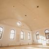 The main room of the Sabile Makslas Culture and Tourism Center from the inside with white walls and wooden window frames