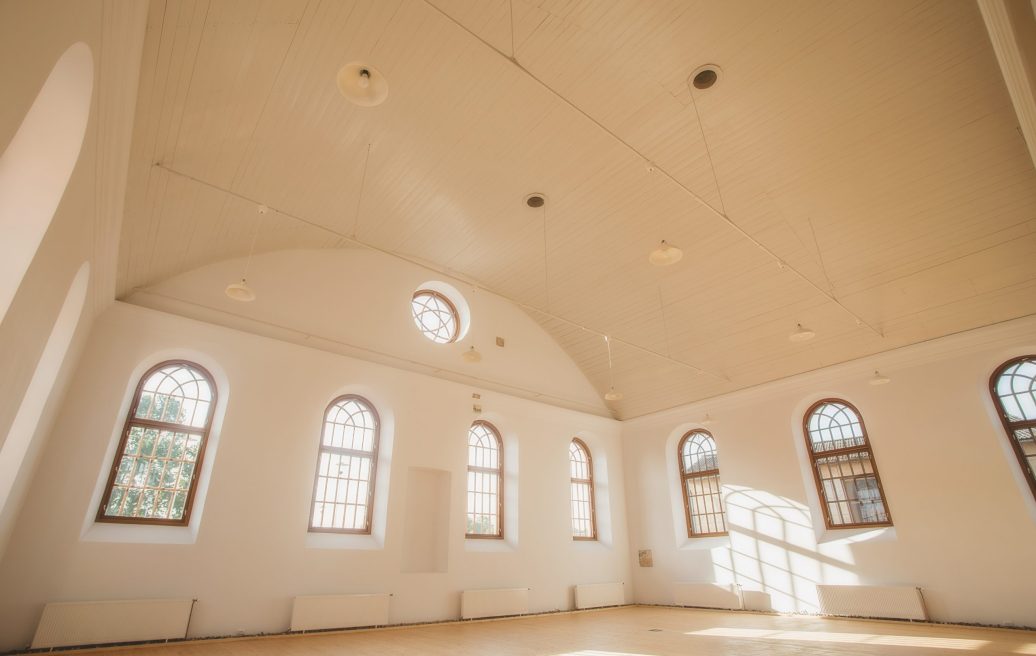 The main room of the Sabile Makslas Culture and Tourism Center from the inside with white walls and wooden window frames