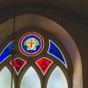 St. John’s Church in Cēsis window stained glass with red, blue and yellow elements and a cross