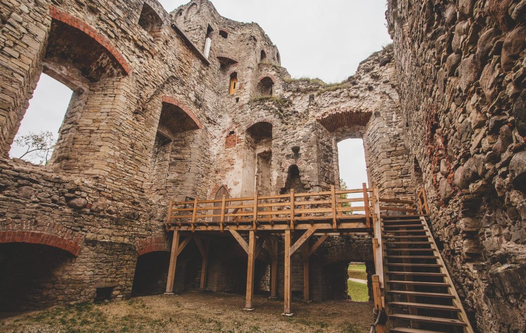 The courtyard of the medieval castle of Cēsis, showing the attraction, as well as the visitor's walkway with stairs leading to the top