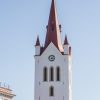 St. John’s Church in Cēsis tower with a cross at the top of the spire, church clock and windows