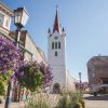 St. John’s Church in Cēsis Church building from the outside with the city in the background and purple flowers in the town square