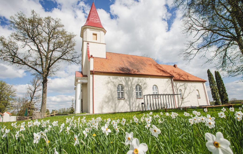 Side view of Rubene Evangelical Lutheran Church on a summer day with flowers in the foreground