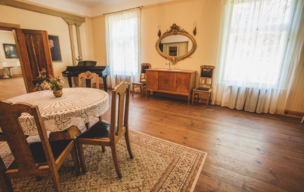 Ungurmuiža guest room with mirror, table, piano