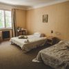 Ungurmuiža bedroom with two beds, chair, window, lamp, table and white curtains