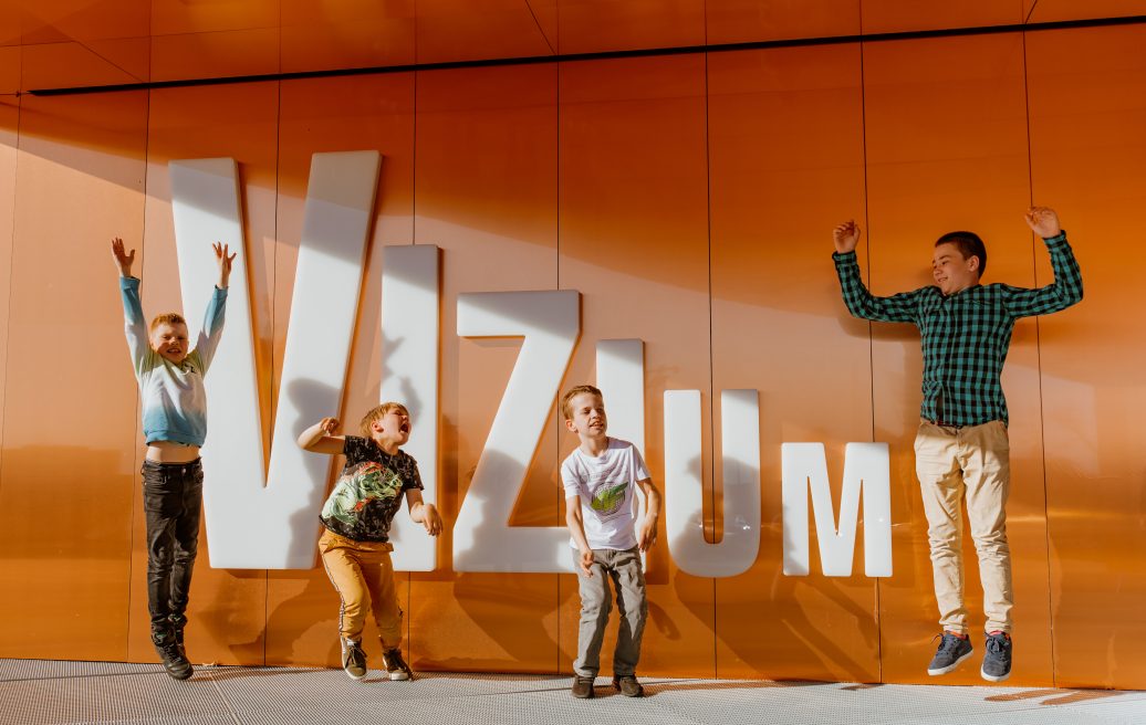 Students jumping in front of the Vizium logo of the Science Center