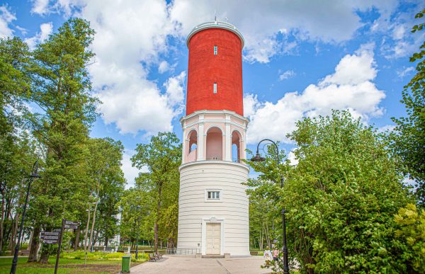 Ķemeri water tower against a blue sky background among green leafy trees
